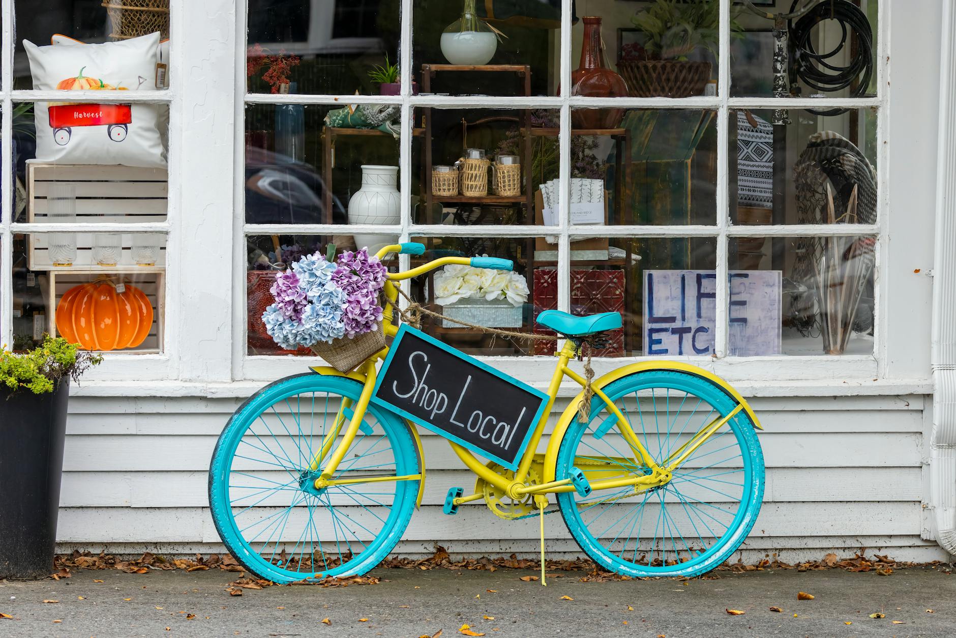 Kolorowy rower z kwiatami i napisem Shop Local przed sklepem