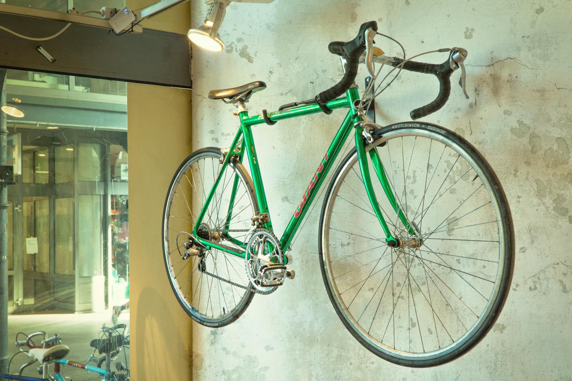 Zielony vintage rower wyścigowy wiszący na ścianie w showroomie rowerowym