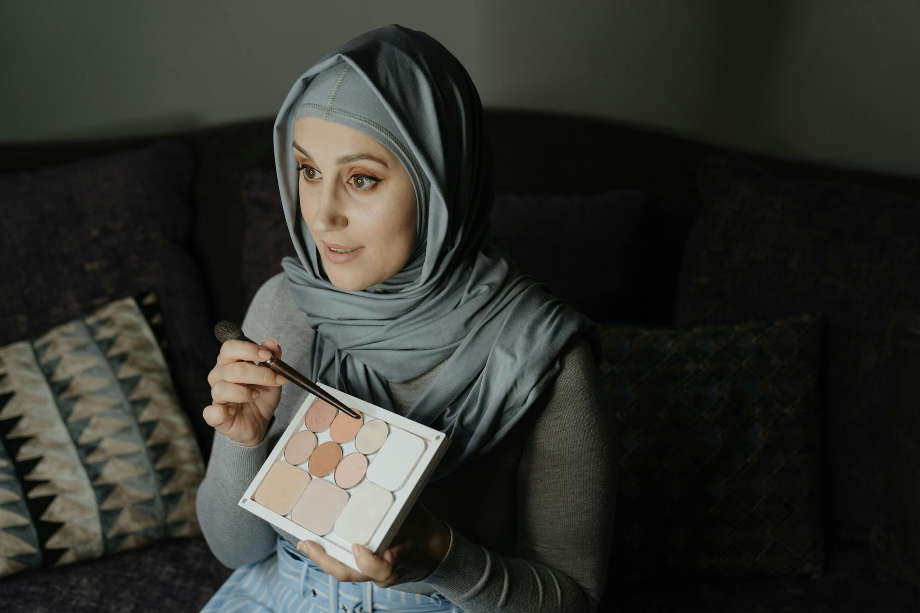 Kobieta w hijabie nakłada jasny cień na powieki w dziennym makijażu