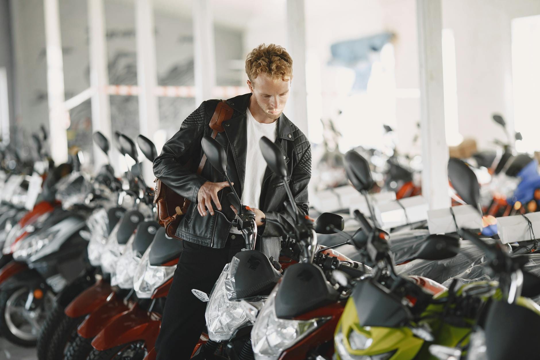 Mężczyzna ogląda w salonie rząd motocykli, rozważając zakup