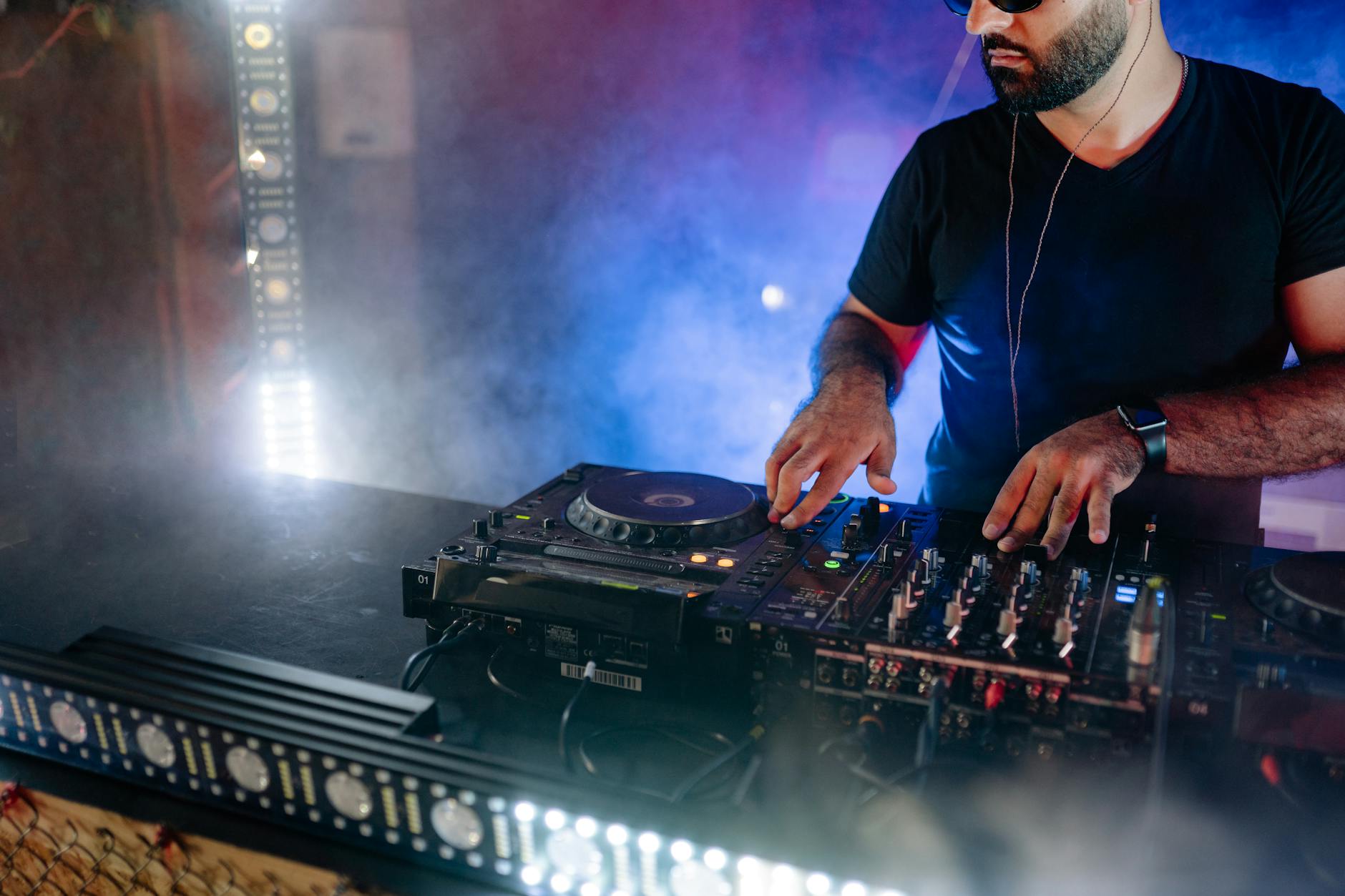 DJ przy konsolecie gra energiczny set w kolorowym klubie DJ przy konsolecie gra energiczny set w kolorowym klubie