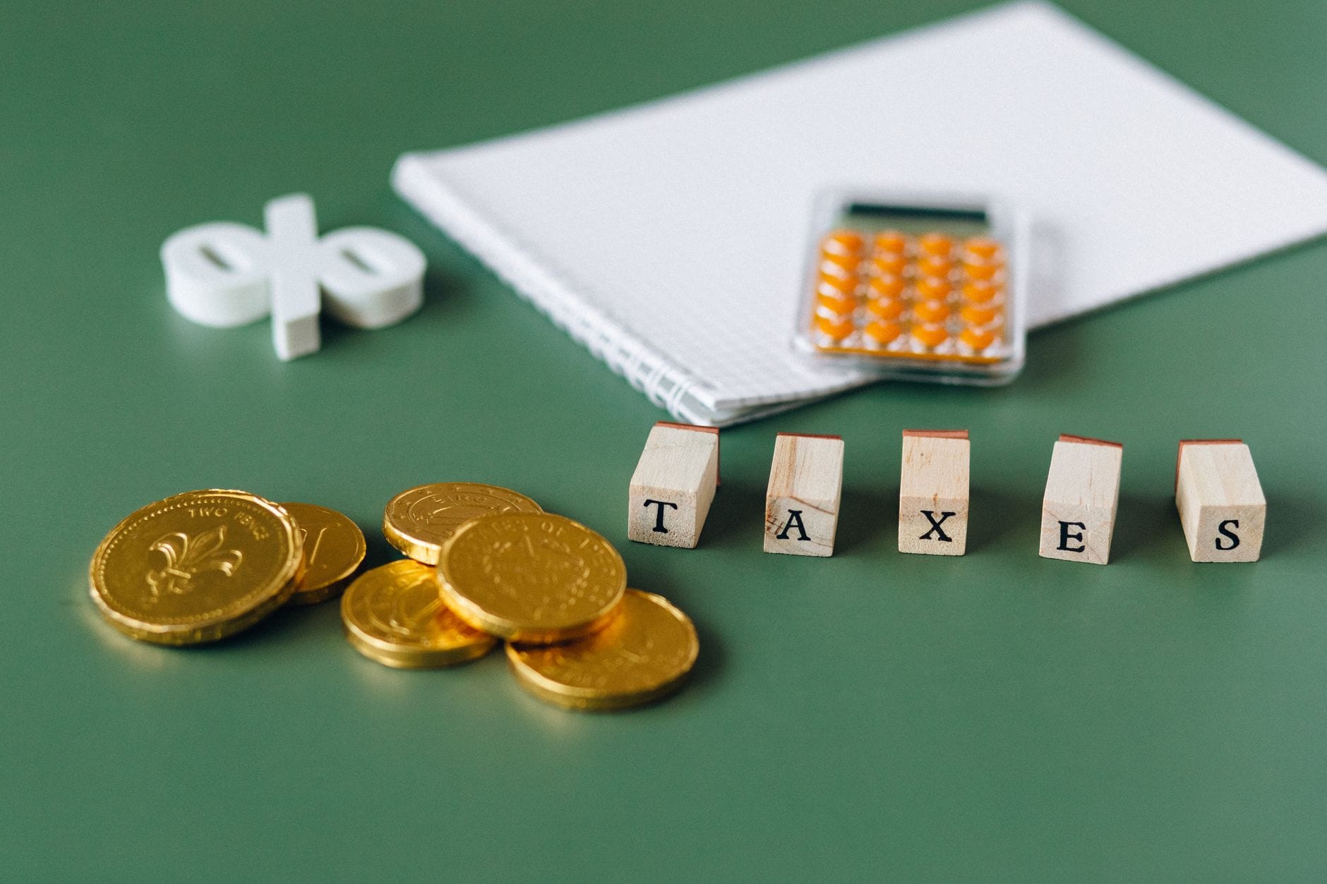 Monety, kalkulator i napis taxes na zielonym tle